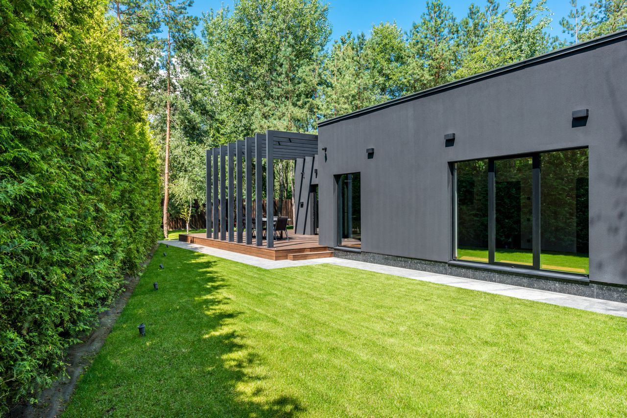 Mastering the First Impression: Your intriguing post title goes here Contemporary house exterior with spacious lawn and pergola, set in a serene outdoor environment.